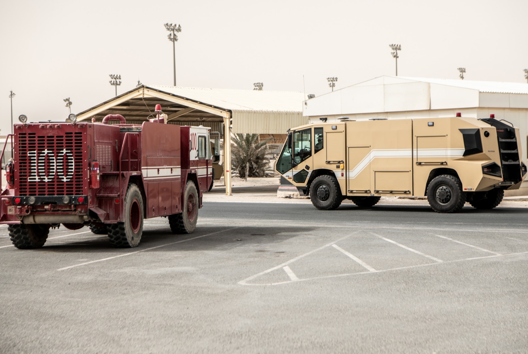 a red firetruck and a desert tan firetruck outside