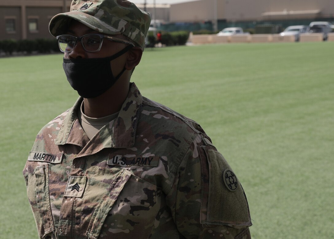 Army Reserve Sgt. Anika Martin, 310th Sustainment Command (Expeditionary), stands at parade rest at the March 21, 2021 recognition ceremony for the 328 U.S. and coalition military personnel, who earned the Norwegian Foot March at Camp Arifjan, Kuwait. Martin earned her NFM badge by completing the 18.6-mile course with a 25-pound ruck in 5 hours and 6 minutes. (U.S. Army photo by Staff Sgt. Neil W. McCabe)