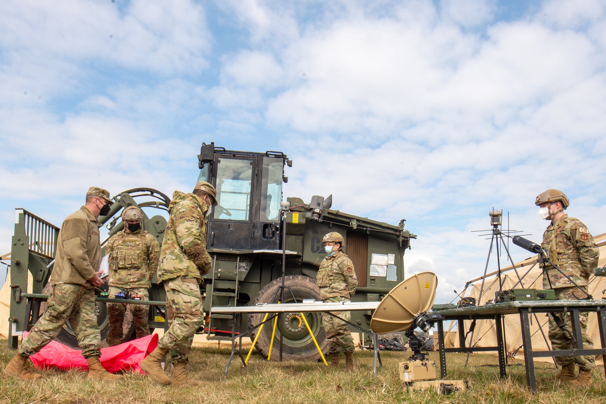 Military members outside with equipment on tables.