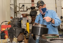 Photo of a man standing at a work bench while he repairs the wheel hub for the automated guided vehicles.