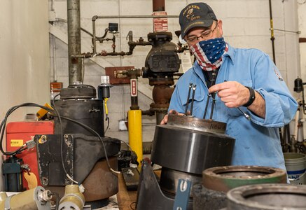 Photo of a man standing at a work bench while he repairs the wheel hub for the automated guided vehicles.