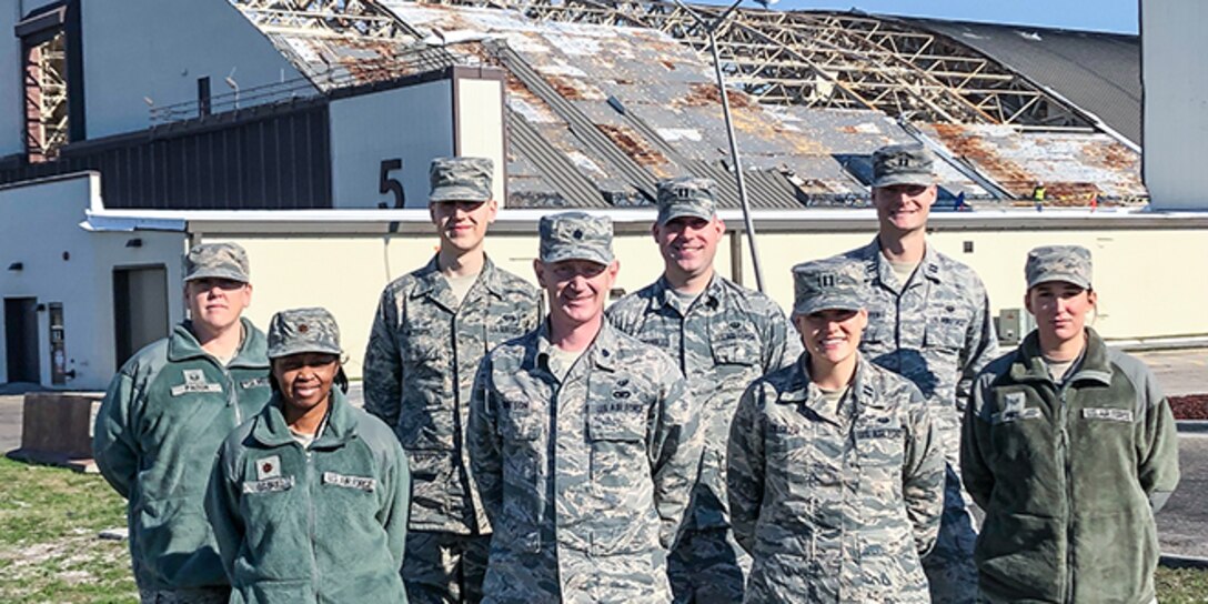 8 members of the Tyndall Legal Office standing in front of Hangar 5 after Hurricane Michael