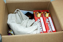 Soldier care package items are seen in a box prior to shipment at the Maj. Gen. Emmett J. Bean Federal Center in Indianapolis March 6, 2021. Army Soldiers, civilian employees, veterans and retirees came together to make care packages, which will be sent to deployed Soldiers of the U.S. Army Reserve’s 310th Expeditionary Sustainment Command. (U.S. Army photo by Mark R. W. Orders-Woempner)