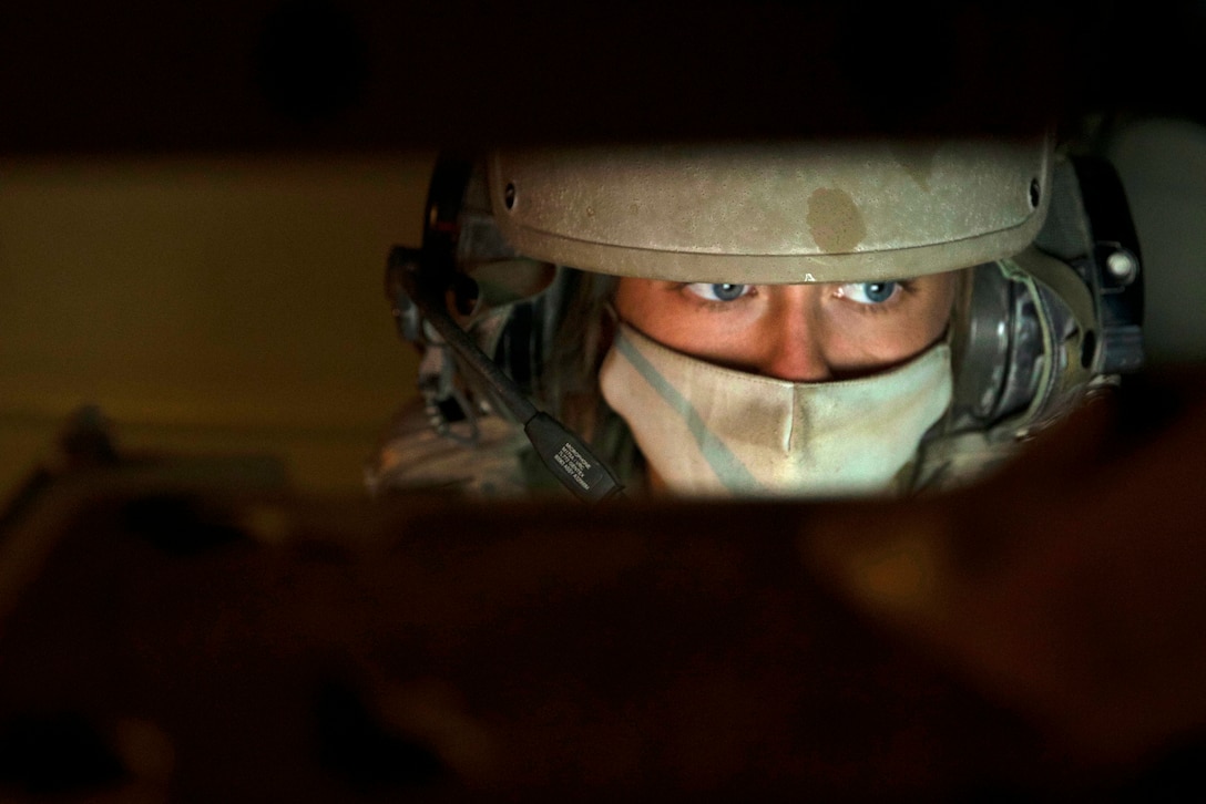 A soldier wearing a mask is seen while looking at a screen.