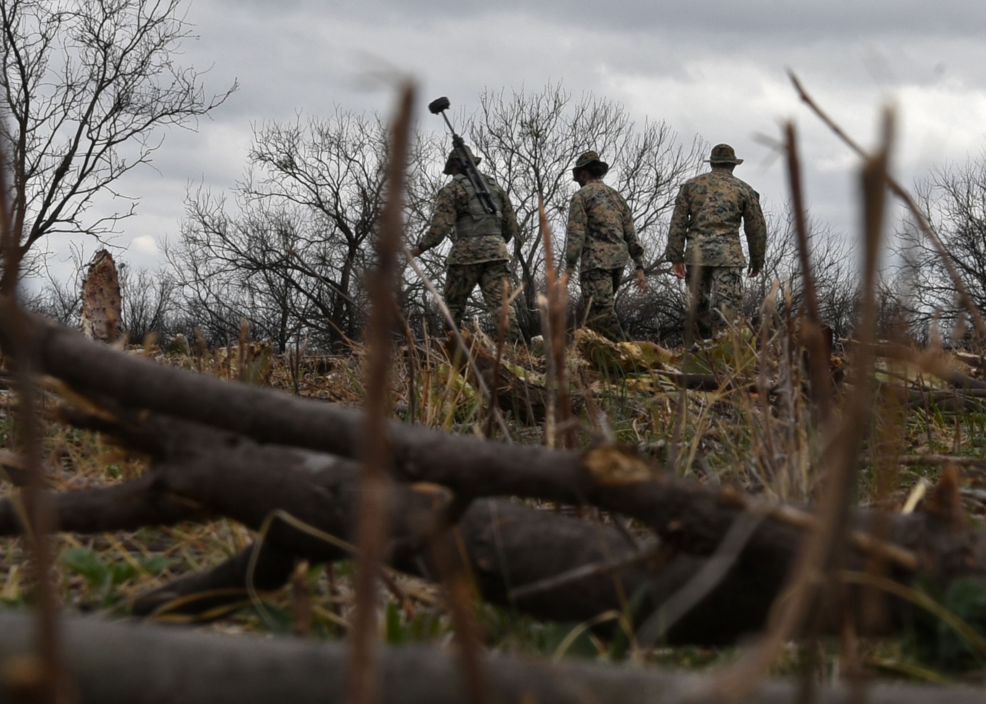 U.S. Marine Corps Tactical Signals Intelligence Operator course students from the Marine Corps Detachment, snake through brush and debris during an intelligence field exercise outside of the MCD dormitories on Goodfellow Air Force Base, Texas, March 22, 2021. The students operated in small teams, which were designed to optimize the training curriculum and simulated real-life scenarios. (U.S. Air Force photo by Senior Airman Abbey Rieves)
