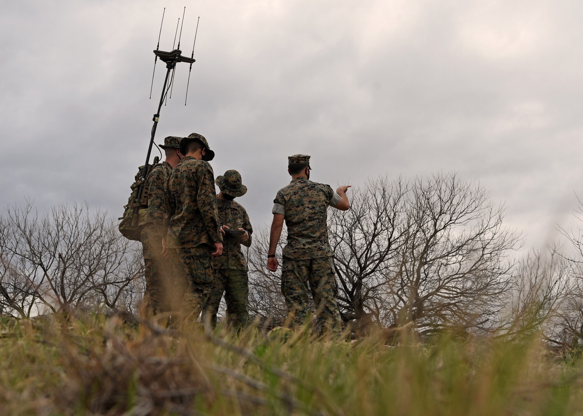 U.S. Marine Corps Gunnery Sgt. Zachary Fulk, Marine Corps Detachment Tactical Signals Intelligence Operator course instructor, offers insight and recommends new techniques for the TSOC students, who are locating an enemy signal emitter with their versatile radio observation and direction finder during a field exercise outside of the MCD dormitories on Goodfellow Air Force Base, Texas, March 22, 2021. Fulk and other MCD instructors were trained to challenge their students in order to promote educational attainment and expand warfighting readiness. (U.S. Air Force photo by Senior Airman Abbey Rieves)
