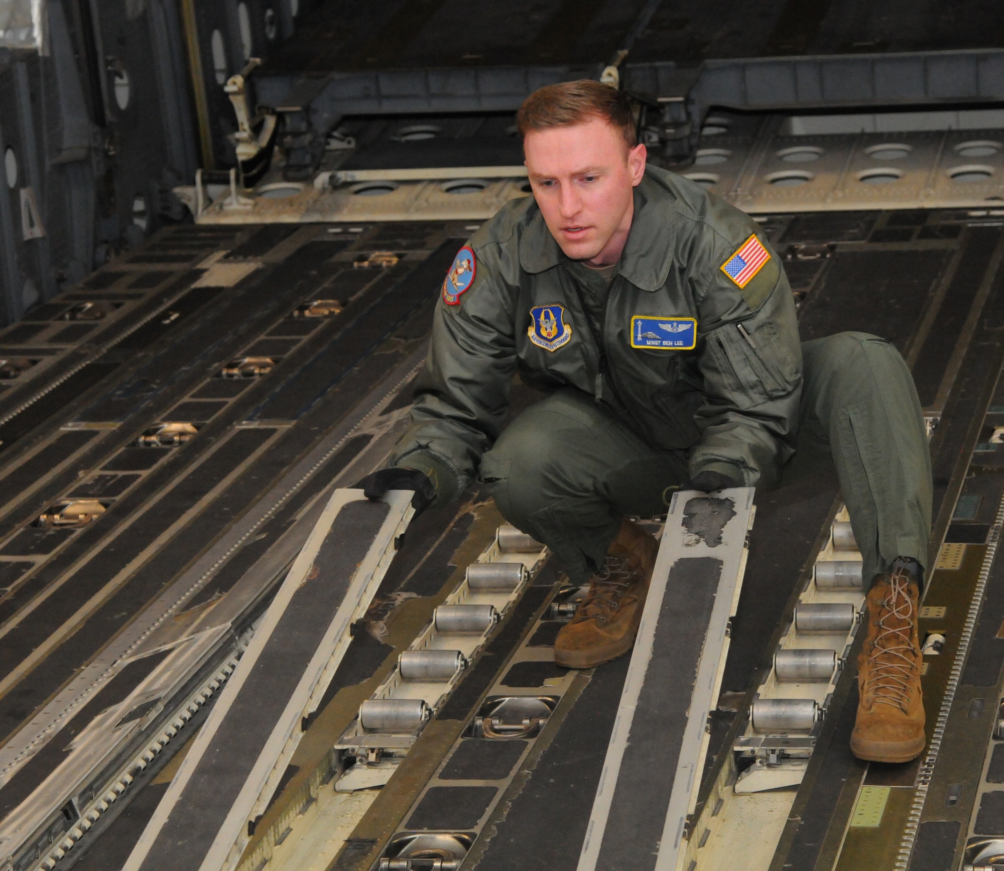 Master Sgt. Benjamin Lee, a loadmaster assigned to the 97th Airlift Squadron here, flips cargo rails rollers on a C-17 Globemaster III to prepare the aircraft for a cargo upload during a local sortie mission March 15, 2021.