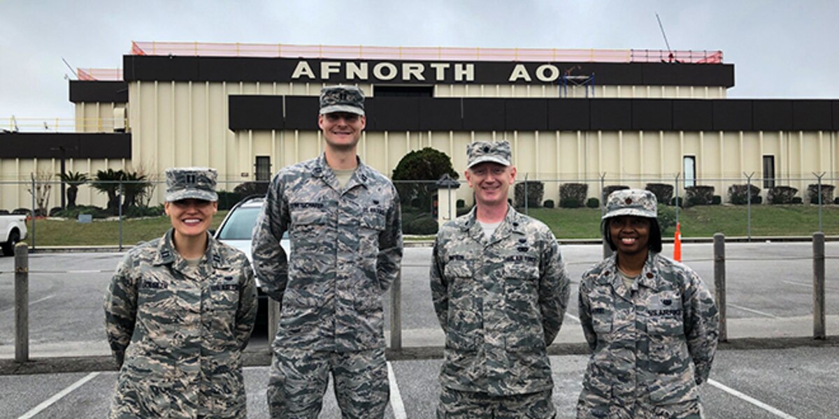 Tyndall Legal Office reunites after Hurricane Michael. Standing in front of damaged building.