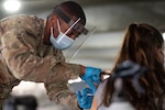 A U.S. Army combat medic administers a COVID vaccine.