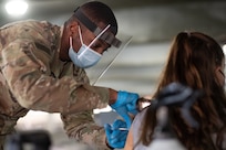 A U.S. Army combat medic administers a COVID vaccine.