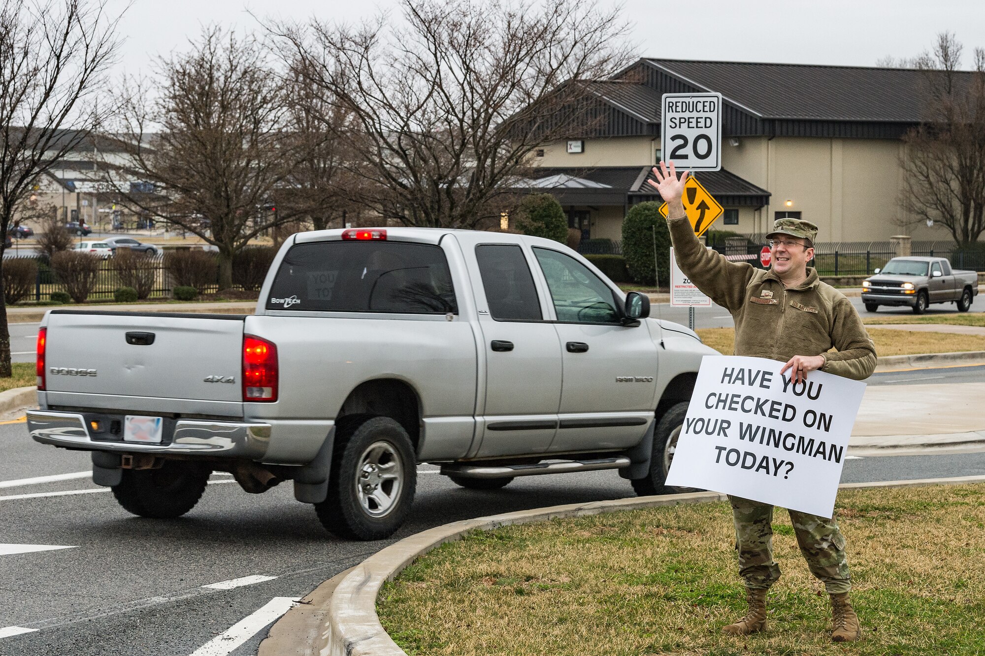 Master Sgt. Lance Tressler, 436th Airlift Wing religious affairs superintendent, holds a sign displaying a positive affirmation as vehicles approach the main gate on Dover Air Force Base, Delaware, March 24, 2021. Tressler and other members of Team Dover held signs as personnel approached the base. (U.S. Air Force photo by Roland Balik) (This photo has been altered for security purposes by blurring out personal identifiable information.)