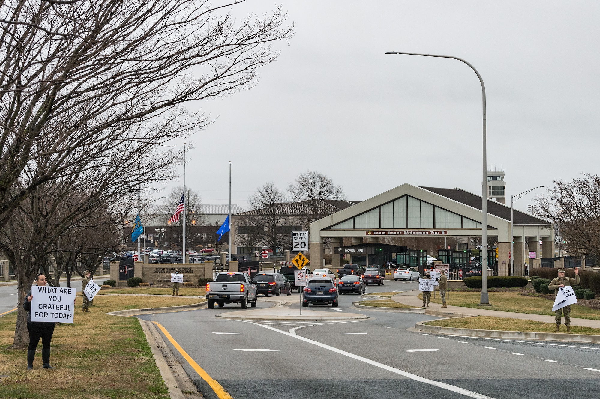 Members of Team Dover hold signs displaying positive affirmations as vehicles approach the main gate on Dover Air Force Base, Delaware, March 24, 2021. Those holding signs encouraged drivers with positive messages as they entered base. (U.S. Air Force photo by Roland Balik) (This photo has been altered for security purposes by blurring out personal identifiable information.)