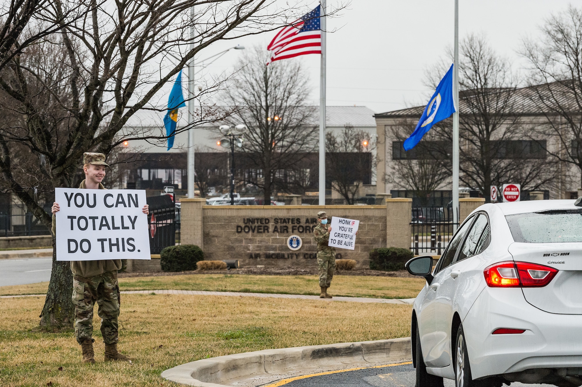 Airman 1st Class Dylan Williams, 436th Airlift Wing religious affairs Airman, holds a sign displaying a positive affirmation as vehicles approach the main gate on Dover Air Force Base, Delaware, March 24, 2021. Williams and other members of Team Dover held signs as personnel approached the base. (U.S. Air Force photo by Roland Balik)