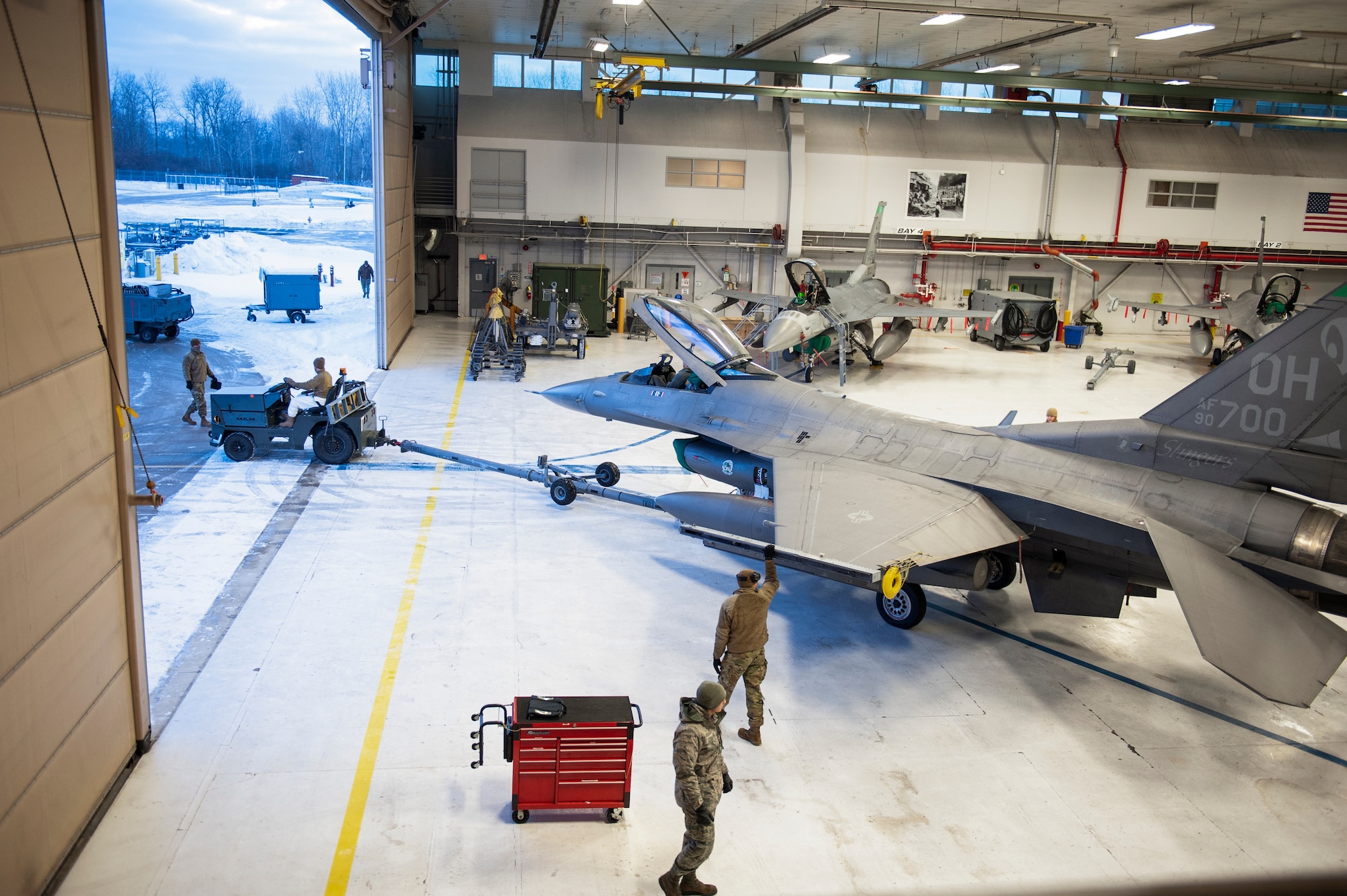 U.S. Air Force F-16 maintenance personnel, assigned to the Ohio National Guard’s 180th Fighter Wing, begin to tow jets from the hangar, to the flightline, in preparation for early morning training sorties, Feb. 7, 2021.