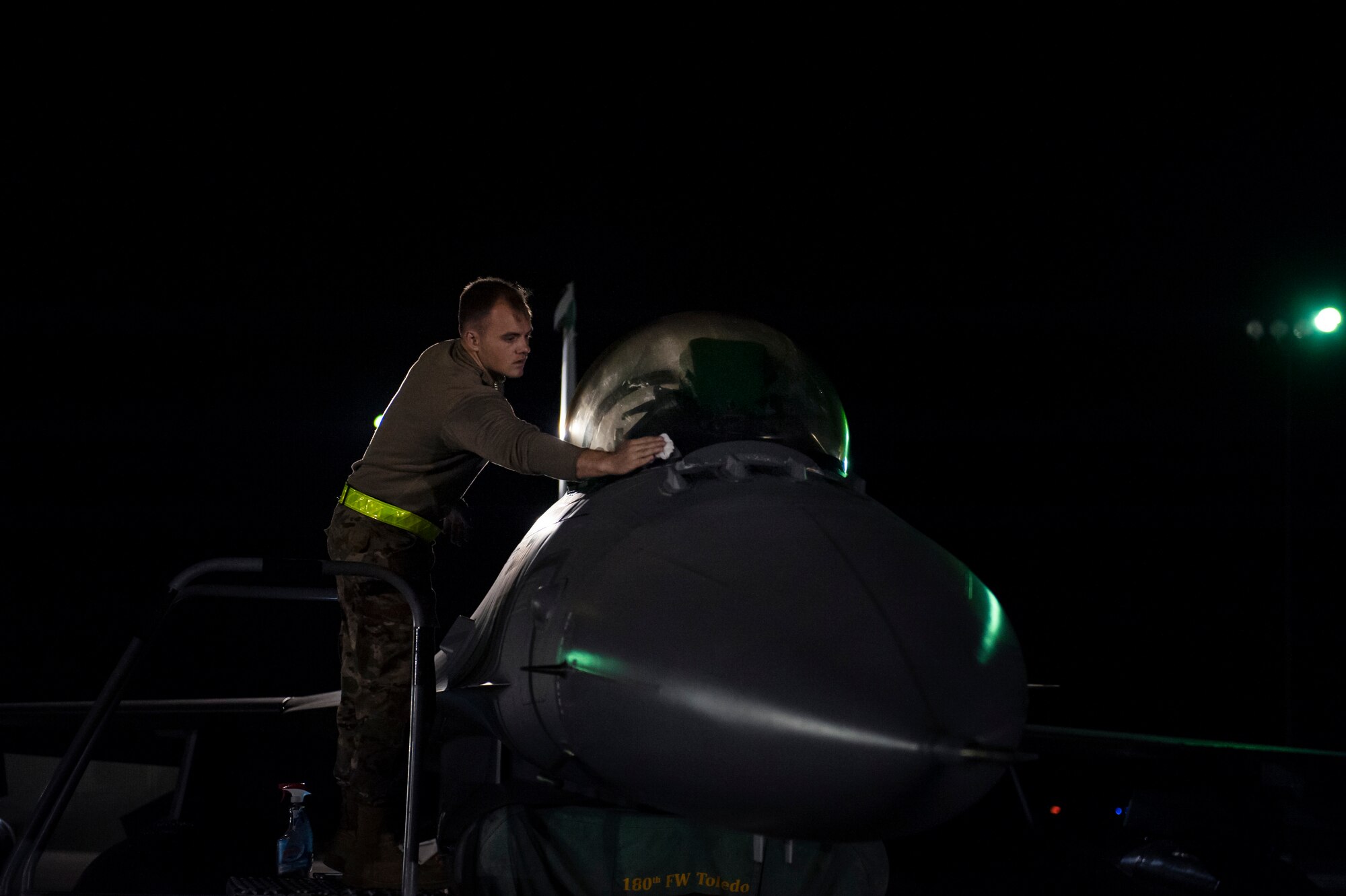 A U.S. Air Force Airman, assigned to the Ohio National Guard’s 180th Fighter Wing, cleans the canopy of an F-16 Fighting Falcon fighter jet prior to an early morning launch, Oct. 12, 2020, as they depart from the 180FW in Swanton, Ohio, for an Aerospace Expeditionary Force deployment.