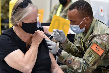 Private Anoumou Game (right), a 68C Practical Nursing Specialist student assigned to the 264th Medical Battalion, 32nd Medical Brigade, U.S. Army Medical Center of Excellence, administers the COVID-19 vaccine to a patient. Game completed Phase 1 of his Advanced Individual Training and is assisting Brooke Army Medical Center inoculating patients.