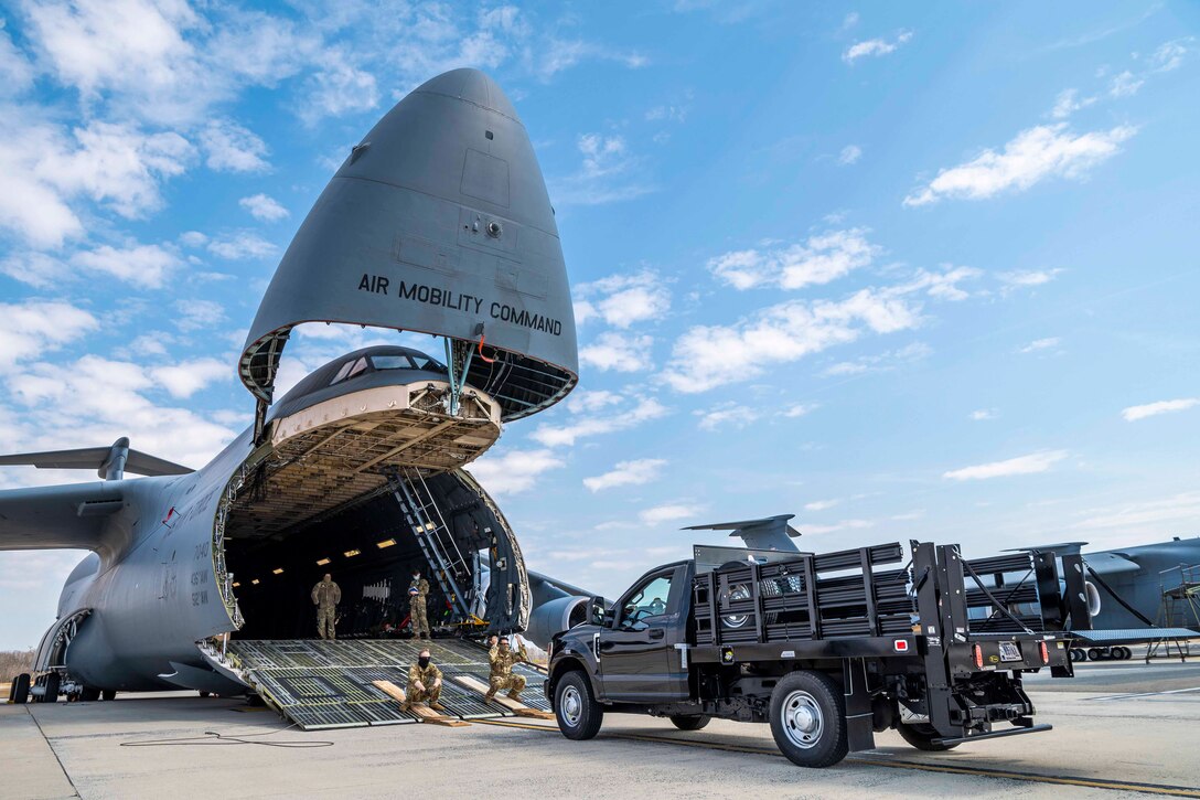 Airmen stand inside the back of an aircraft as a truck prepares to drive in.