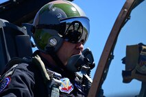 Photo of an Air Force pilot with a helmet on, while sitting in an aircraft cockpit