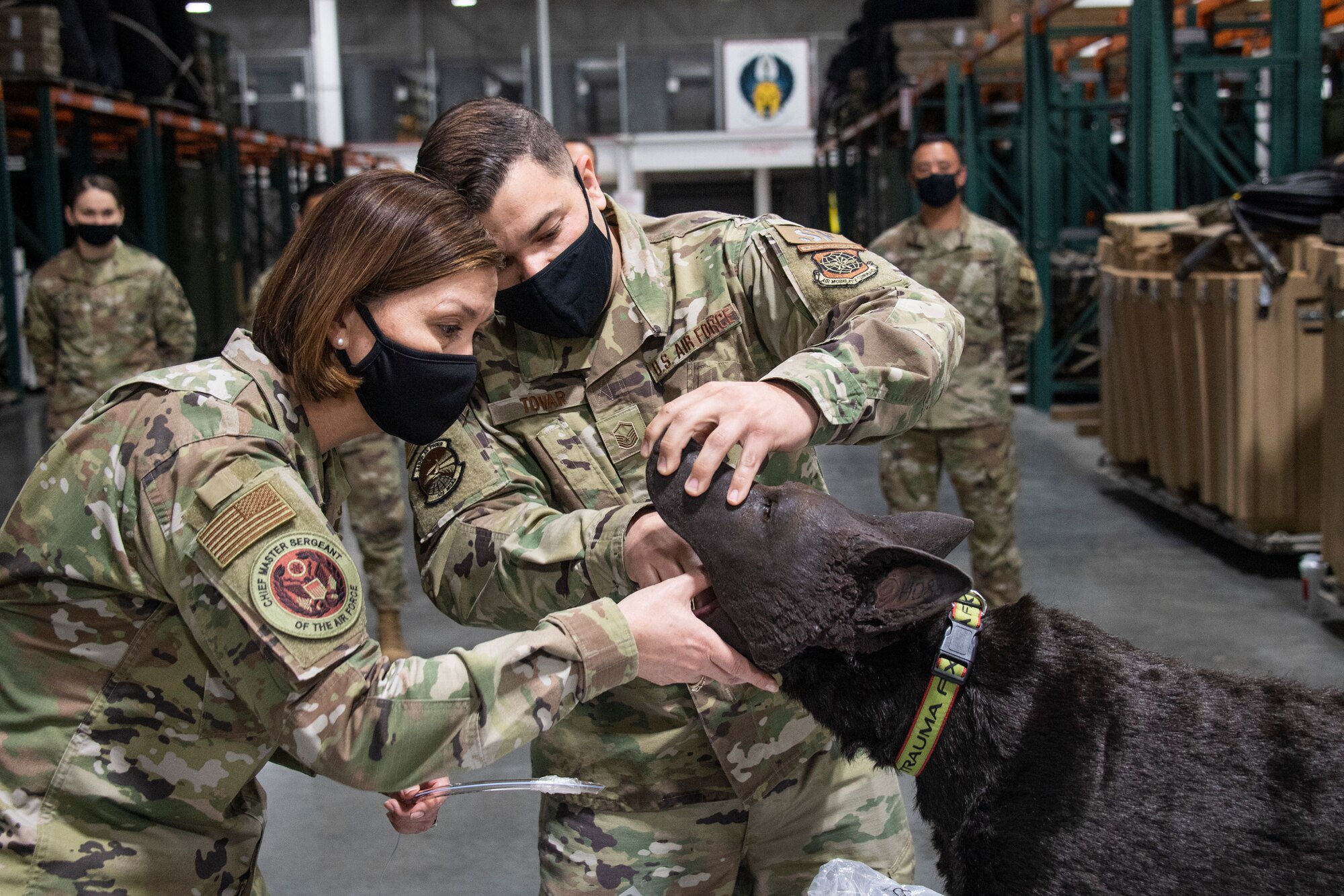 U.S. Air Force Master Sgt. Andres Tovar, 571st Mobility Support Advisory Squadron, right, guides Chief Master Sergeant of the Air Force JoAnne S. Bass, left, as she inserts an intubation tube into the mouth of a K-9 Tactical Combat Casualty Care mannequin during the innovation demonstration, Mar. 24, 2021, at Travis Air Force Base, California. MSAS air advisors provide critical training to partner nation defense forces in Central and South America to support Air Forces Southern counter narcotics mission. (U.S. Air Force photo by Master Sgt. Liliana Moreno)