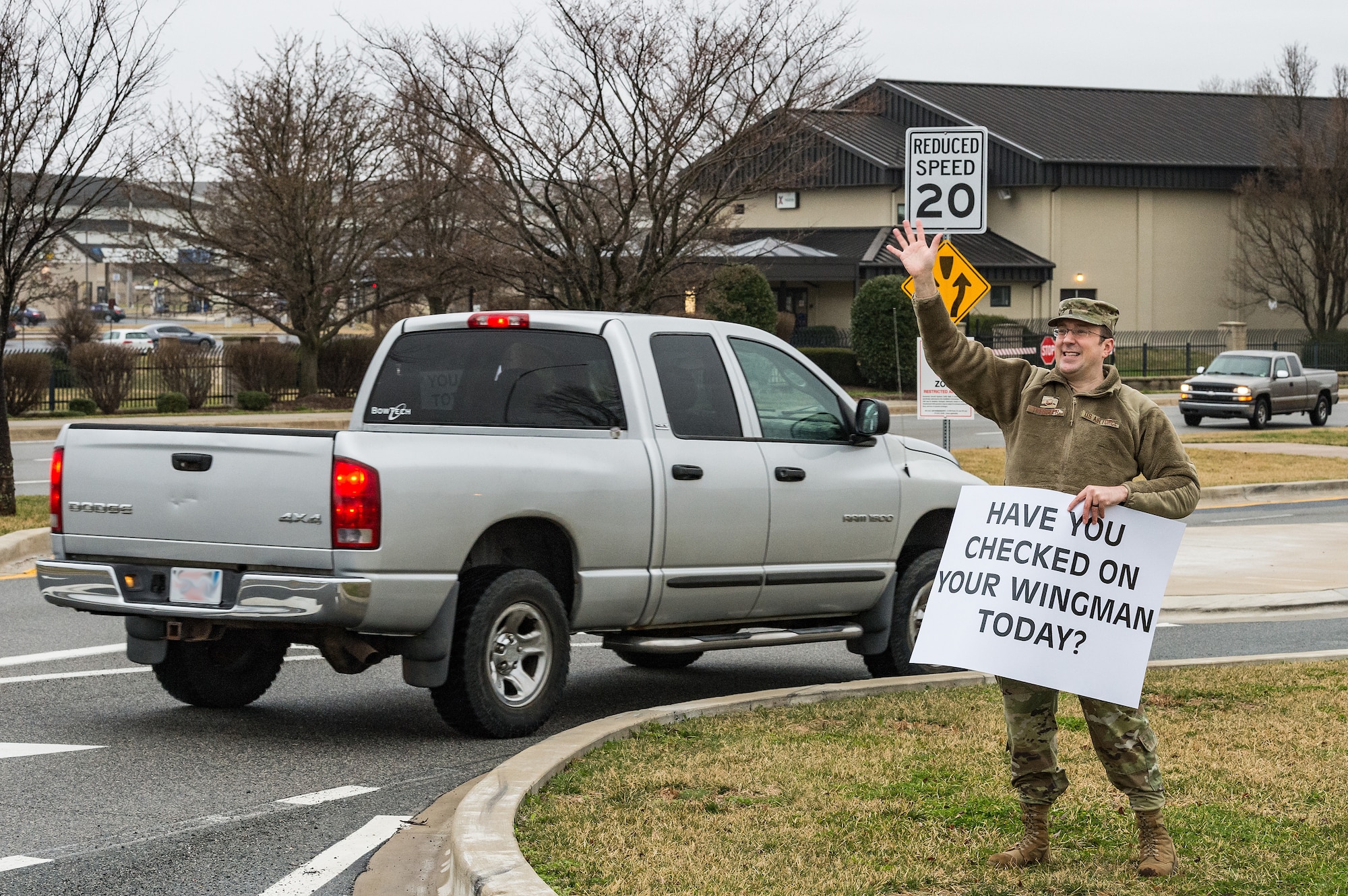 Master Sgt. Lance Tressler, 436th Airlift Wing religious affairs superintendent, holds a sign displaying a positive affirmation as vehicles approach the main gate on Dover Air Force Base, Delaware, March 24, 2021. Tressler and other members of Team Dover held signs as personnel approached the base. (U.S. Air Force photo by Roland Balik) (This photo has been altered for security purposes by blurring out personal identifiable information.)
