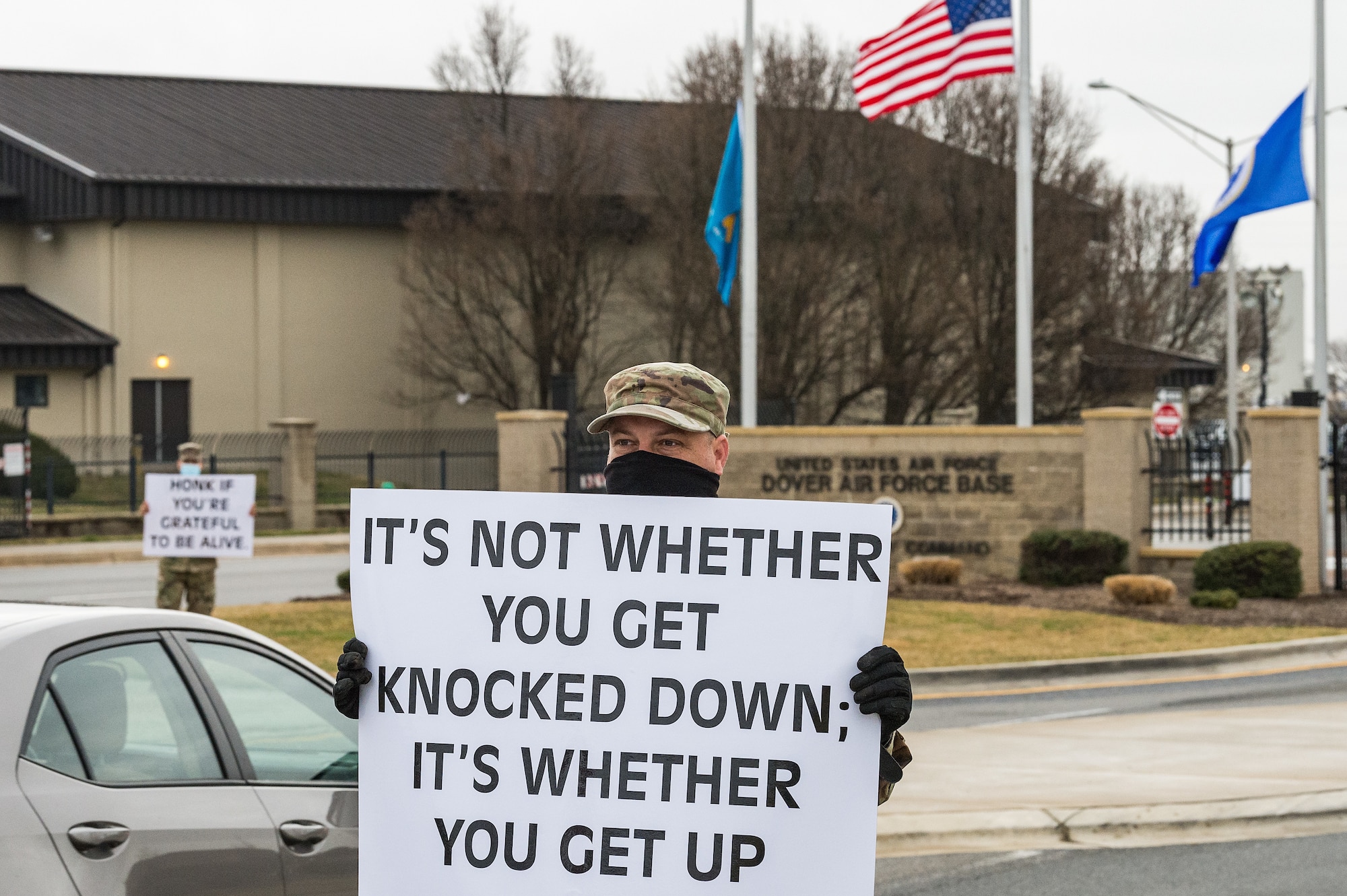 Staff Sgt. Jason Bravard, 436th Airlift Wing religious affairs Airman, holds a sign displaying a positive affirmation as vehicles approach the main gate on Dover Air Force Base, Delaware, March 24, 2021. Bravard and other members of Team Dover held signs as personnel approached the base. (U.S. Air Force photo by Roland Balik)