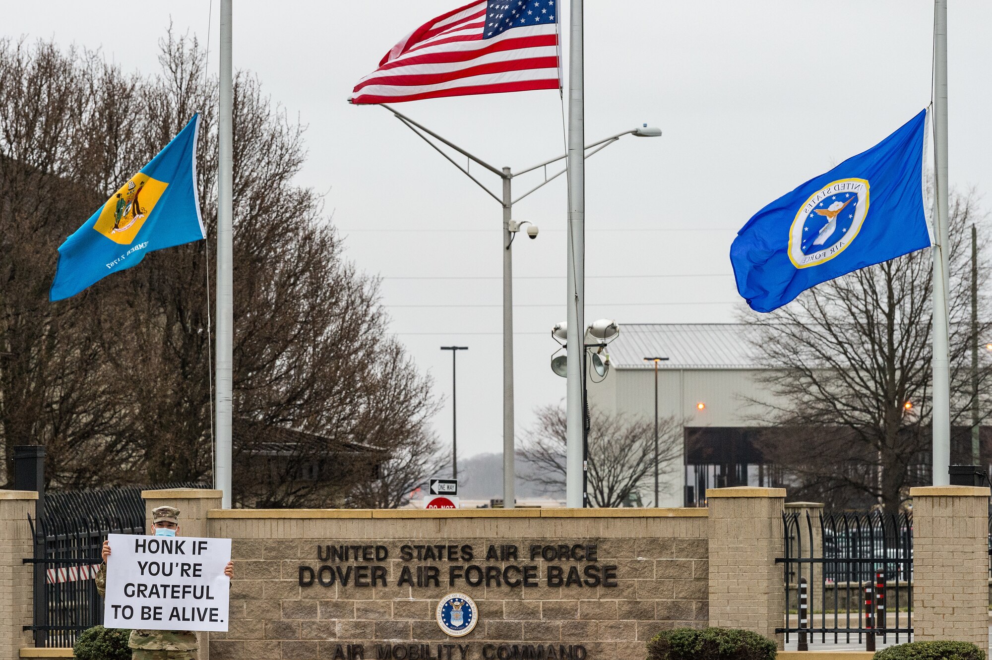 Staff Sgt. Eric Feliciano, 512th Airlift Wing religious affairs Airman, holds a sign displaying a positive affirmation as vehicles approach the main gate on Dover Air Force Base, Delaware, March 24, 2021. Feliciano and other members of Team Dover held signs as personnel approached the base. (U.S. Air Force photo by Roland Balik)