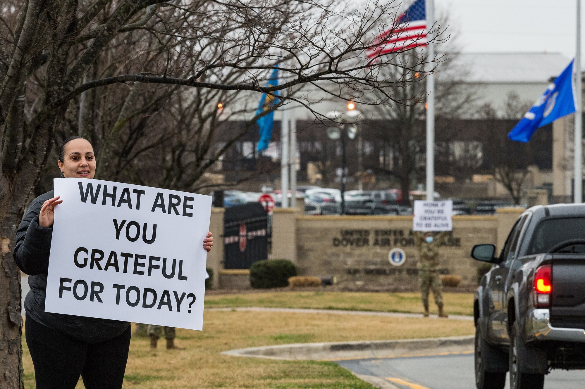 Dr. Mamie Futrell, 436th Airlift Wing community support coordinator, holds a sign displaying a positive affirmation as vehicles approach the main gate on Dover Air Force Base, Delaware, March 24, 2021. Futrell and other members of Team Dover held signs as personnel approached the base. (U.S. Air Force photo by Roland Balik)