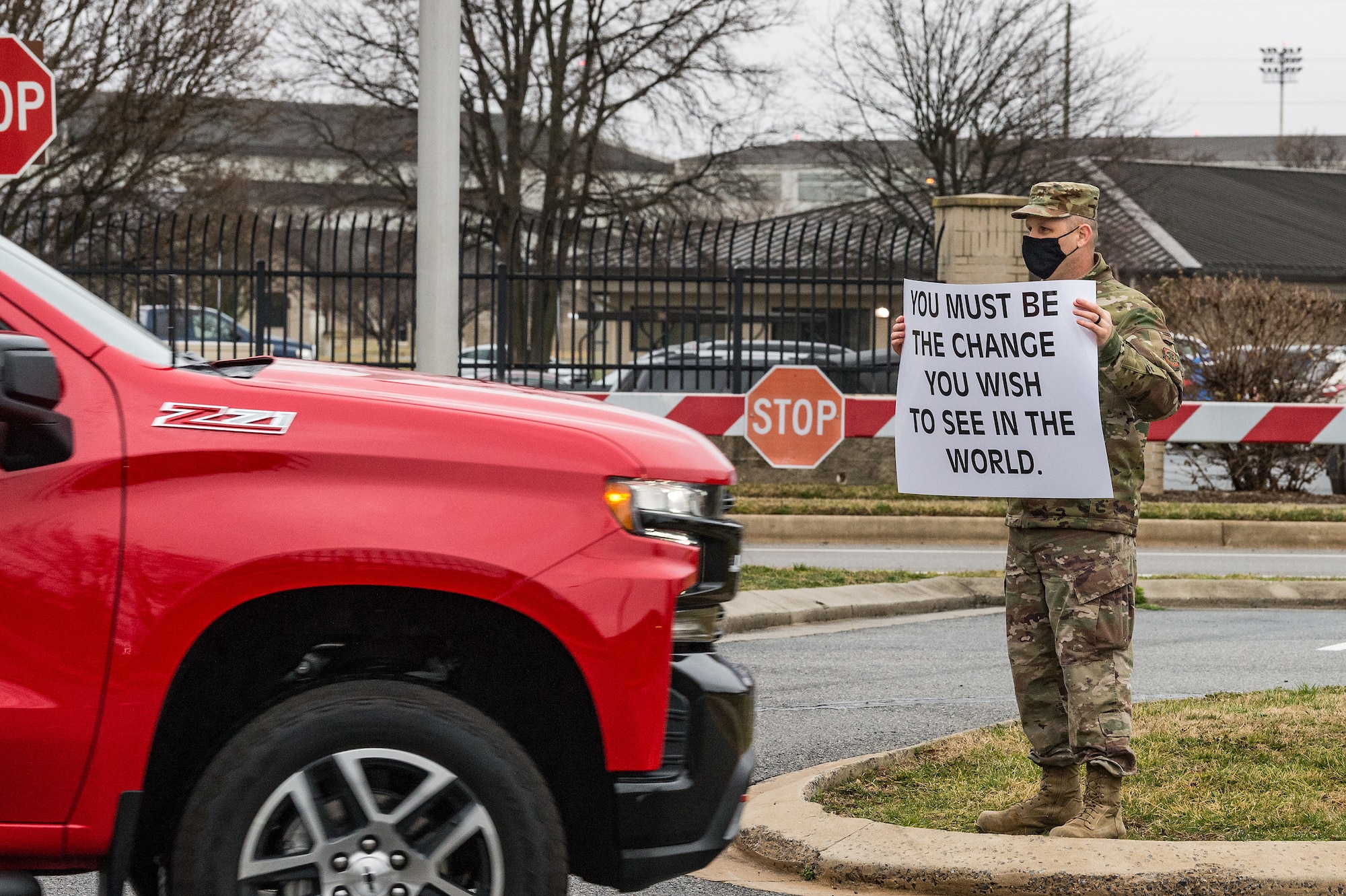 Capt. Jonathan Dawson, 436th Airlift Wing chaplain, holds a sign displaying a positive affirmation as vehicles pass through the main gate on Dover Air Force Base, Delaware, March 24, 2021. Dawson and other members of Team Dover held signs as personnel entered the base. (U.S. Air Force photo by Roland Balik)