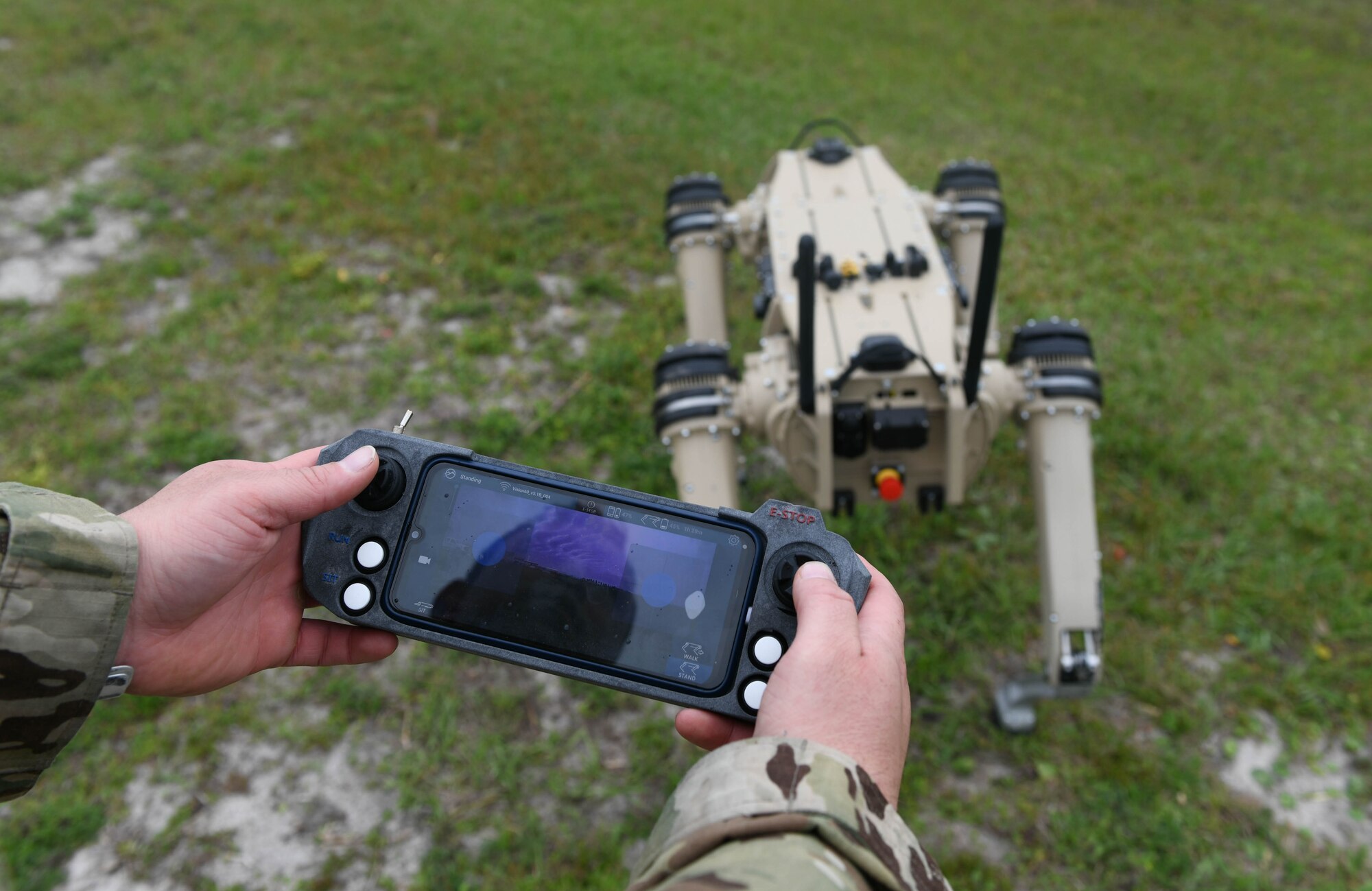Master Sgt. Krystoffer Miller controls a robot dog by a hand-held controller
