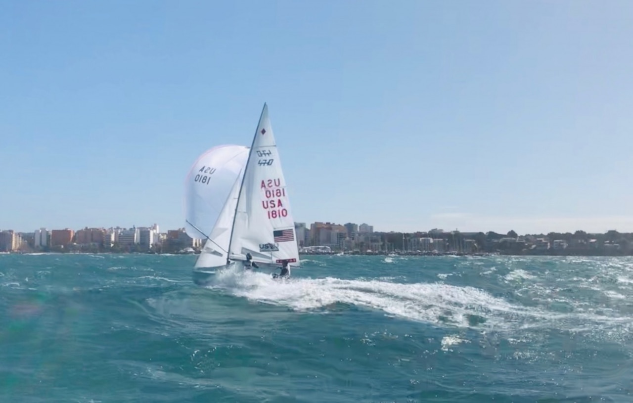 A sail boat sails through choppy blue water.