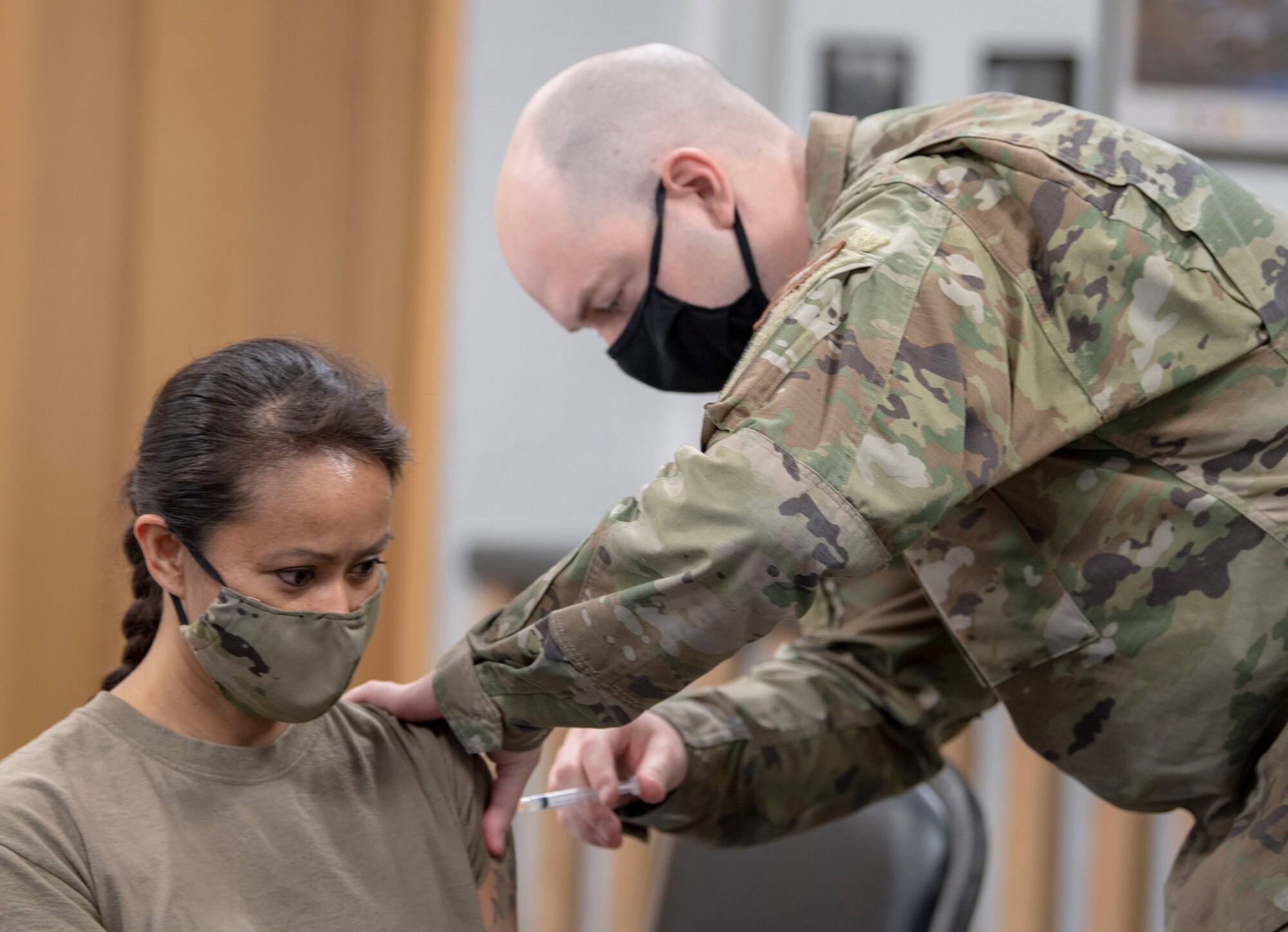 Tech. Sgt. Daniel Potter, 701st Munitions Maintenance Squadron independent duty medical technician (right), administers a COVID-19 vaccine to Capt. Michelle Angeles, 701st MUNSS Mission Support Flight commander, at Kleine Brogel Air Base, Belgium, March 19, 2021. IDMTs are responsible for having a broad spectrum of medical knowledge, and at remote units like Kleine Brogel, they act as the primary care provider for hundreds of Airmen. (U.S. Air Force photo by Senior Airman Alex Miller)