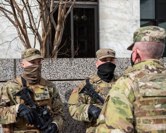 U.S. Army Maj. Gen. Mark Schindler, acting adjutant general of the Pennsylvania National Guard, with back to camera, speaks with Pennsylvania National Guard members in Washington, D.C., Feb., 26, 2021. The National Guard has been requested to continue supporting federal law enforcement agencies with security, communications, medical, evacuation, logistics, and safety support to state, district, and federal agencies through mid-March. (U.S. Air National Guard photo by Senior Airman Zoe M. Wockenfuss)
