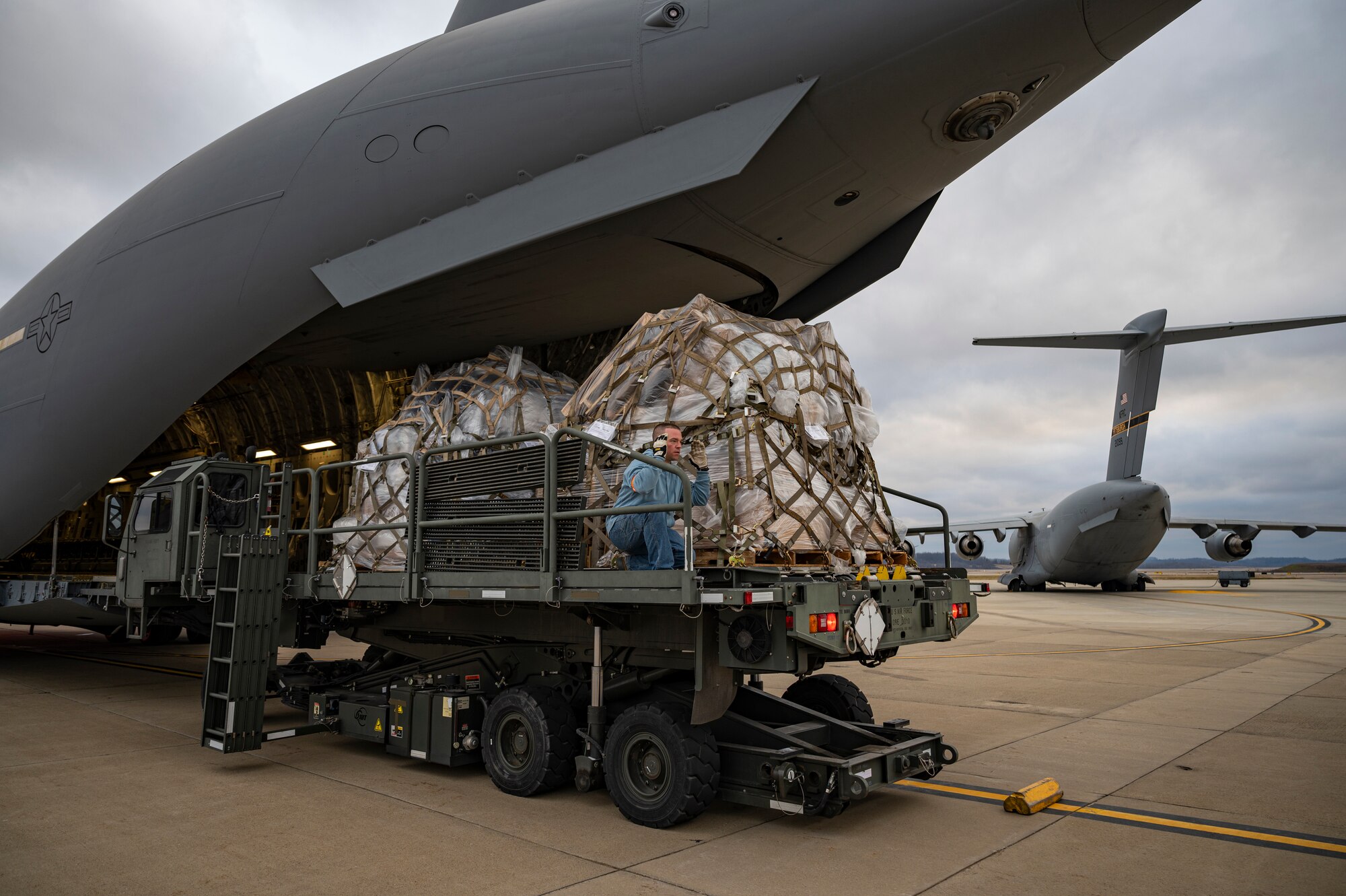 Lance Cooper, 911th Logistics Readiness Squadron traffic manager, directs a Halvorsen Loader to the back of another Halvorsen Loader at the Pittsburgh International Airport Air Reserve Station, Pennsylvania, March 11, 2021.