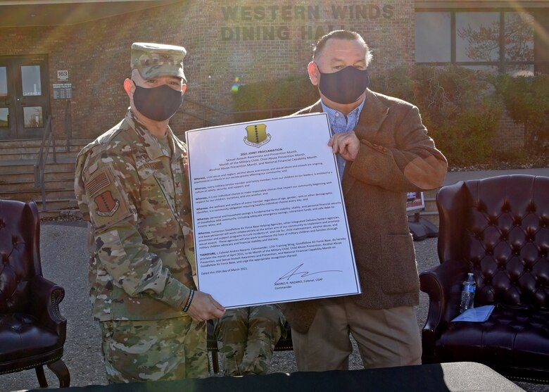 U.S. Air Force Col. Andres Nazario, 17th Training Wing commander, and San Angelo City Councilman, Harry Thomas, hold a signed proclamation at the 2021 Month of Awesomeness and Awareness ceremony outside of the Western Winds Dining Facility, March 25, 2021.  Goodfellow celebrated and re-focused base initiatives towards military children, child abuse prevention, sexual assault prevention and response, alcohol abuse prevention and national financial capability. (U.S. Air Force photo by Senior Airman Abbey Rieves)