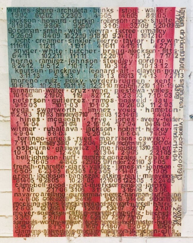 A wooden panel depicting the American flag is inscribed with names and dates.