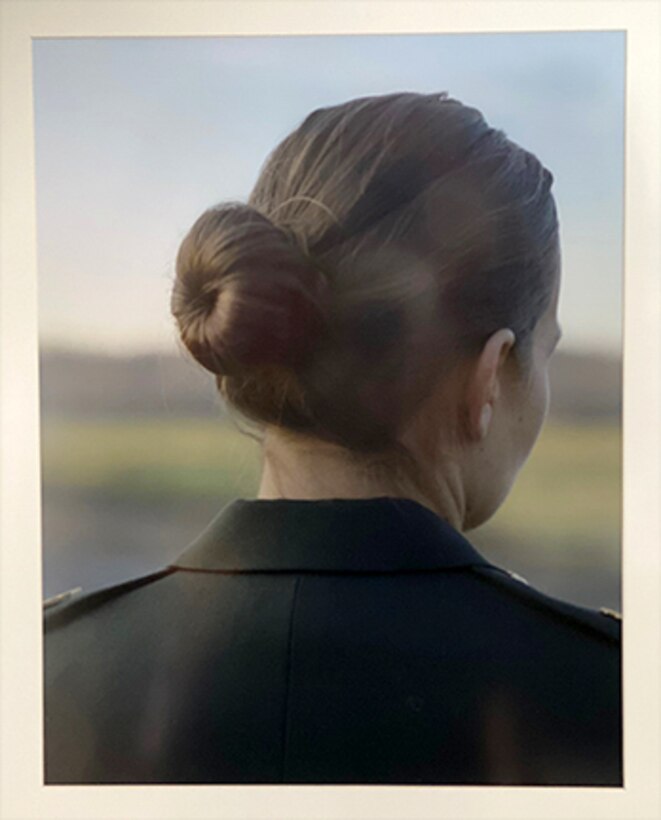 A photo of a woman from behind. Her hair is in a bun.