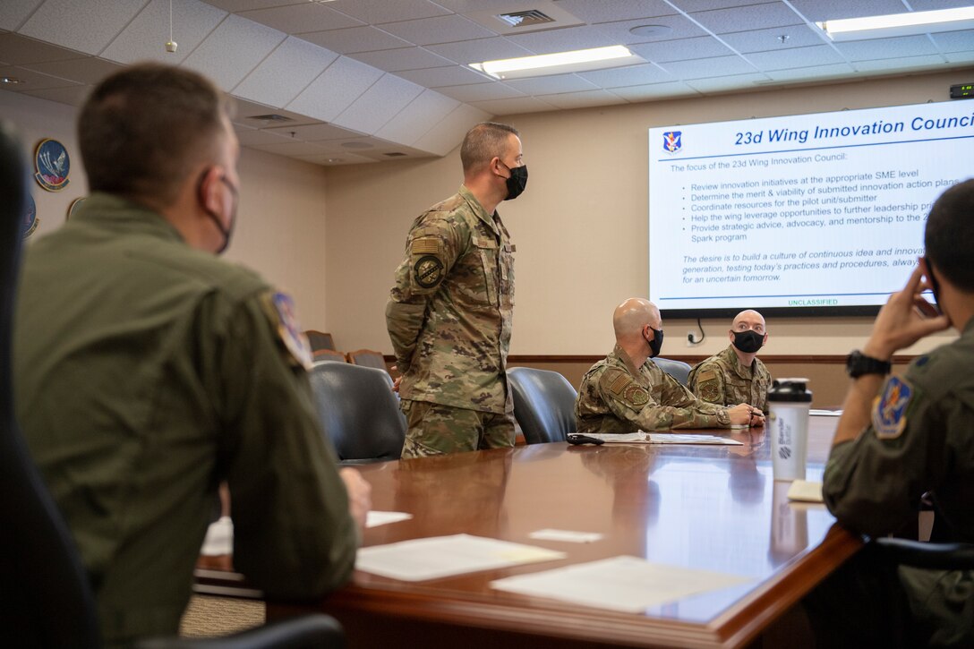 A photo of a man standing next to a table full of Airmen.