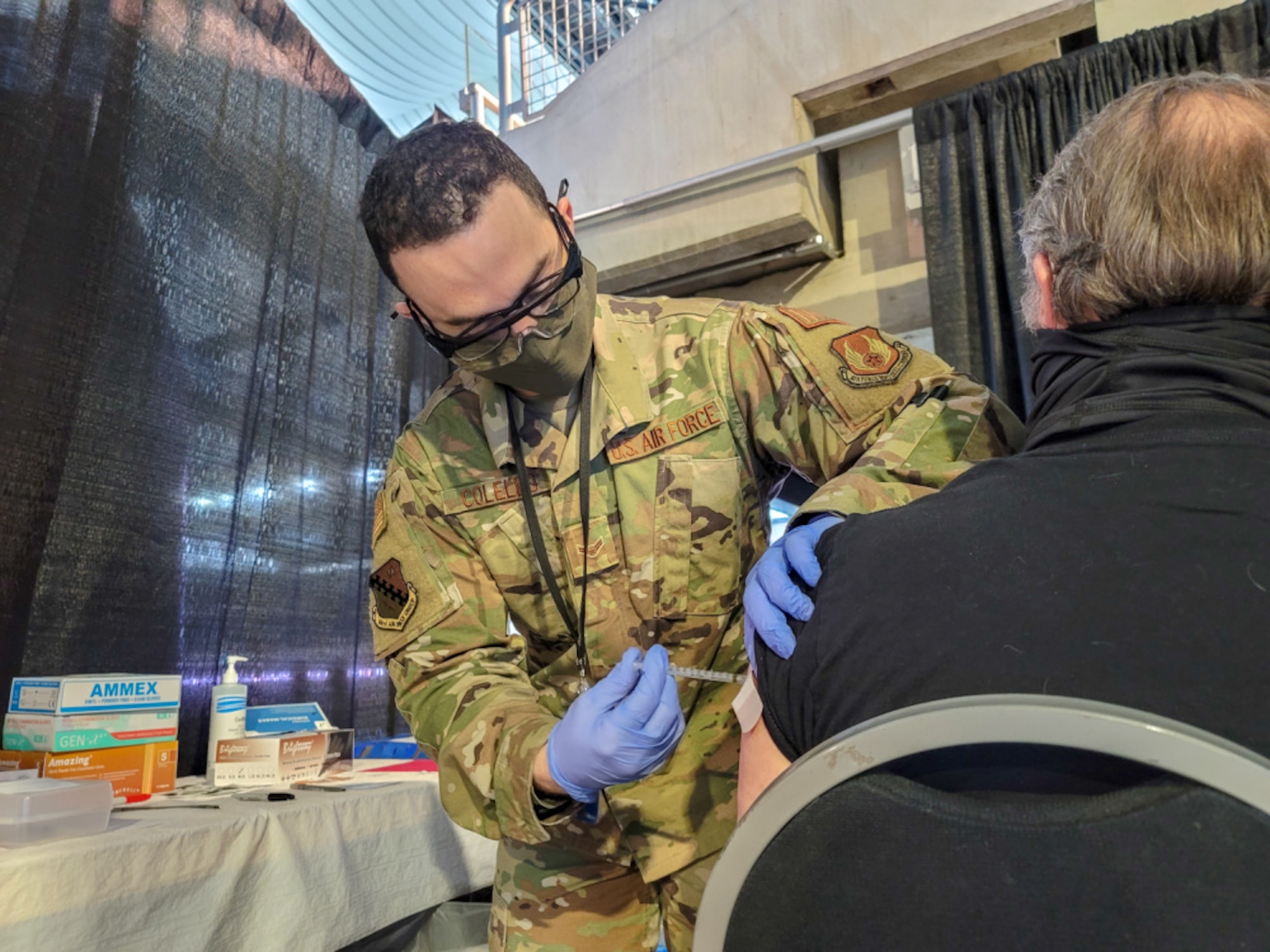 U.S. Air Force Airman 1st Class Charles Colello, 66th Medical Squadron technician, administers a COVID-19 vaccination at the state-run, federally-supported Ford Field Community Vaccination Center in Detroit, March 24. A team of technicians, nurses, and a pharmacist from Hanscom Air Force Base, Mass., deployed to Detroit to support a federal COVID-19 vaccination effort to vaccinate up to 6,000 people a day. (U.S. Army photo by Spc. Laurie Ellen Schubert)