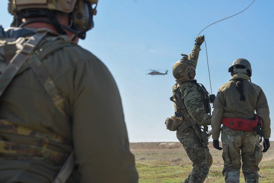 A man and woman prepare to be hoisted up into a helicopter