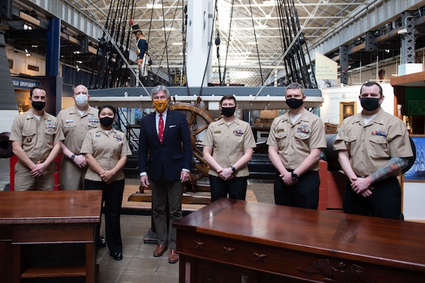 Former Secretary of the Navy, Kenneth J. Braithwaite, poses with Seabees during an executive desk presentation event at the National Museum of the U.S. Navy.