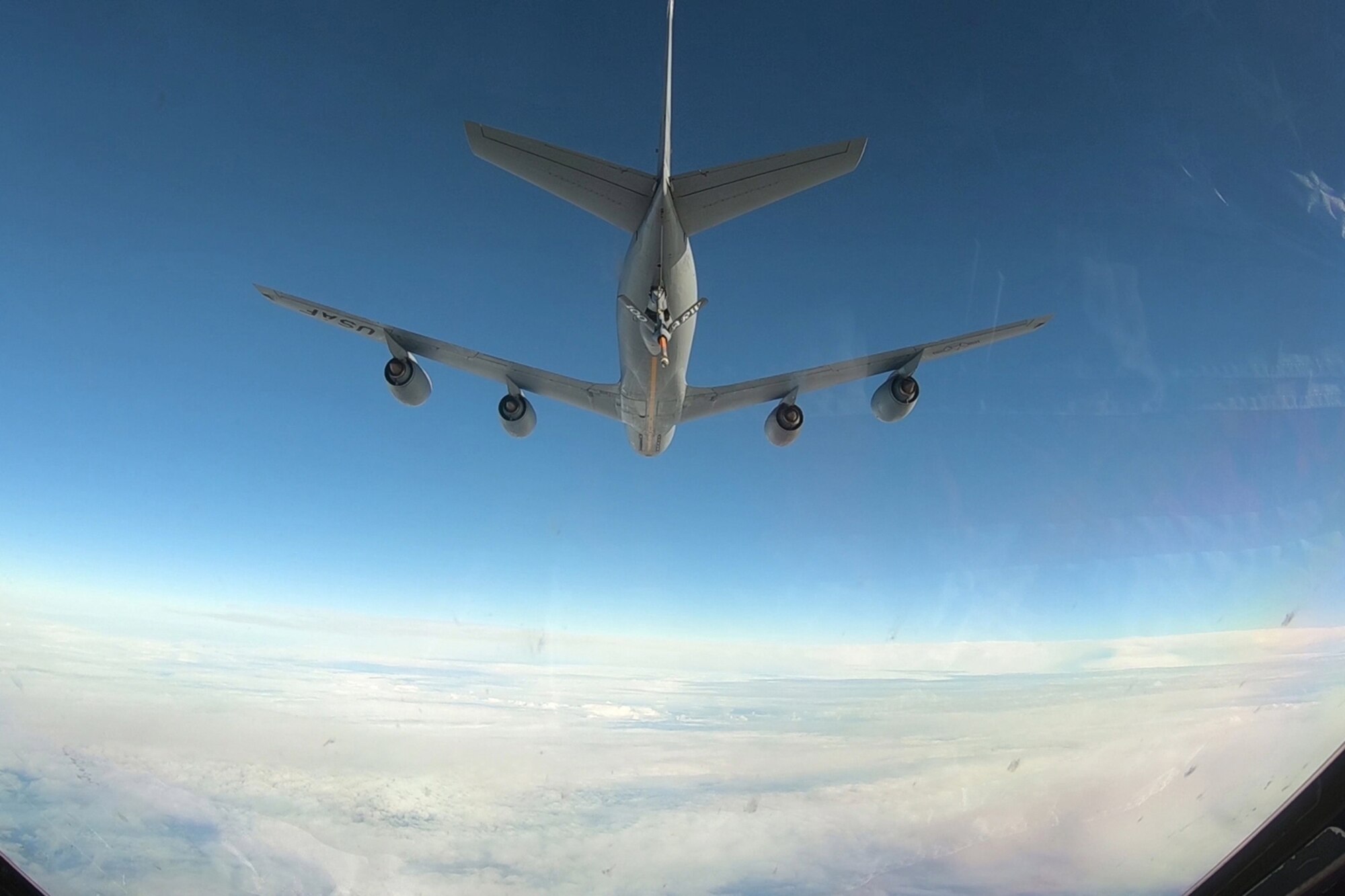 Photo of a KC-135 Stratofortress flying with its fuel boom extended.