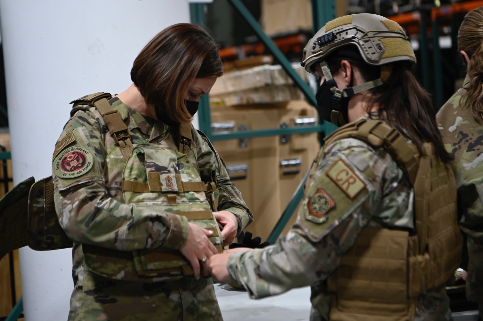 U.S. Air Force Staff Sergeant Emily Kuusinen, 921st Contingency Response Squadron supply representative, secures a vest on Chief Master Sergeant of the Air Force JoAnne S. Bass March 24, 2021, at Travis Air Force Base, California. Chief Bass visited Travis AFB to meet the Airmen who demonstrate innovative thinking and enhance the rapid global mobility mission. (U.S. Air Force photo by Senior Airman Karla Parra)