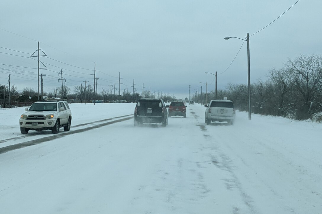 Cars drive on a snowy street.