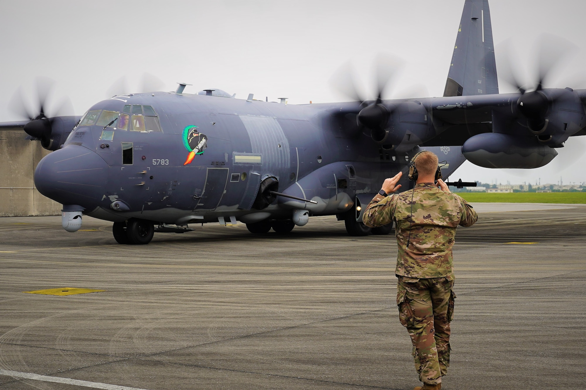 An Airman from the 73rd Special Operations Squadron marshals an AC-130J Ghostrider to its parking location after landing at Kadena Air Base.