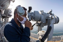 Operations Specialist Seaman Dave Desir monitors maritime traffic while standing lookout watch as amphibious assault ship USS Makin Island (LHD 8) arrives Duqm, Oman, for a maintenance and sustainment visit, March 23.