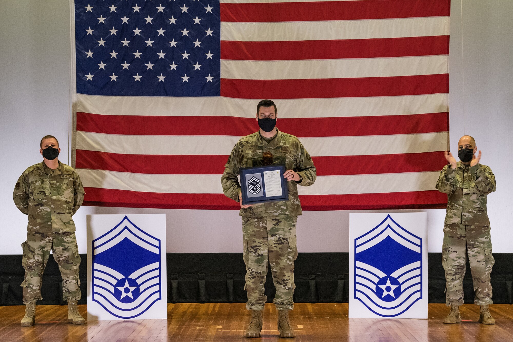 Master Sgt. William Goede, 736th Aircraft Maintenance Squadron assistant aircraft maintenance unit superintendent, stands between Col. Matthew Jones, 436th Airlift Wing commander, left, and Chief Master Sgt. Jeremiah Grisham, 436th AW interim command chief, as they pose for a photo during the senior master sergeant promotion release ceremony held at the base theater on Dover Air Force Base, Delaware, March 26, 2021. Goede was one of 10 master sergeants at Dover AFB selected for promotion to senior master sergeant in the 21E8 promotion cycle. (U.S. Air Force photo by Roland Balik)