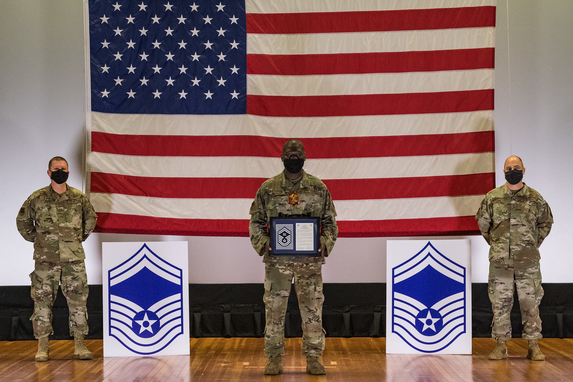 Master Sgt. Zwide Spencer, 436th Aircraft Maintenance Squadron advanced programs superintendent, stands between Col. Matthew Jones, 436th Airlift Wing commander, left, and Chief Master Sgt. Jeremiah Grisham, 436th AW interim command chief, as they pose for a photo during the senior master sergeant promotion release ceremony held at the base theater on Dover Air Force Base, Delaware, March 26, 2021. Spencer was one of 10 master sergeants at Dover AFB selected for promotion to senior master sergeant in the 21E8 promotion cycle. (U.S. Air Force photo by Roland Balik)