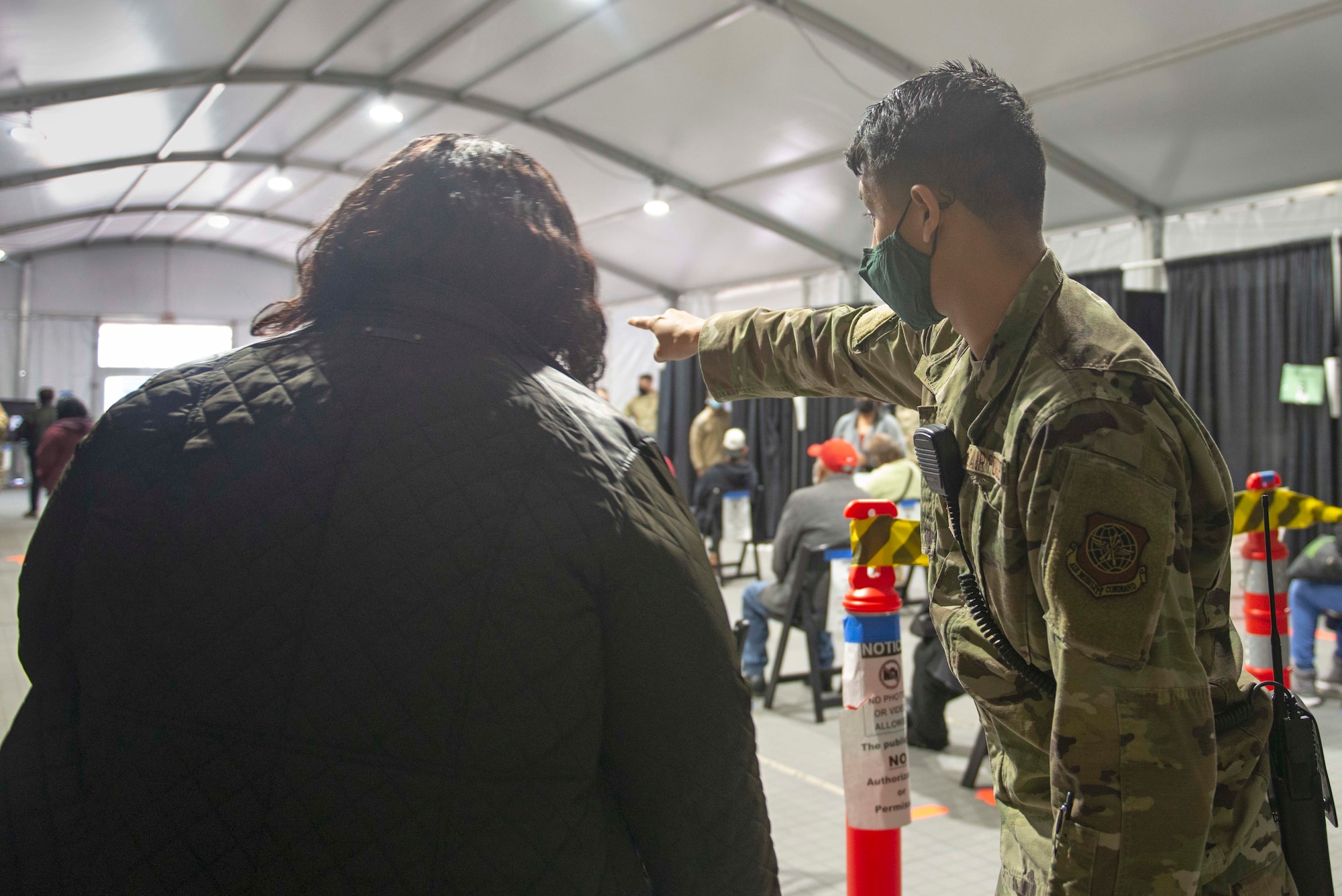 Senior Airman Joshua Acosta, a Roswell, N.M., native and 335th Expeditionary Medical Operations Squadron general purpose Airman, ushers a community member at a Community Vaccination Center in Brooklyn, N.Y., March 22, 2021. Acosta is deployed from the 6th Force Support Squadron out of MacDill Air Force Base, Fla., and is one of approximately 140 Airmen across 28 installations deployed to the Brooklyn CVC in support of U.S. Army North’s COVID-19 response efforts. (U.S. Air Force photo by Tech. Sgt. Ashley Nicole Taylor)