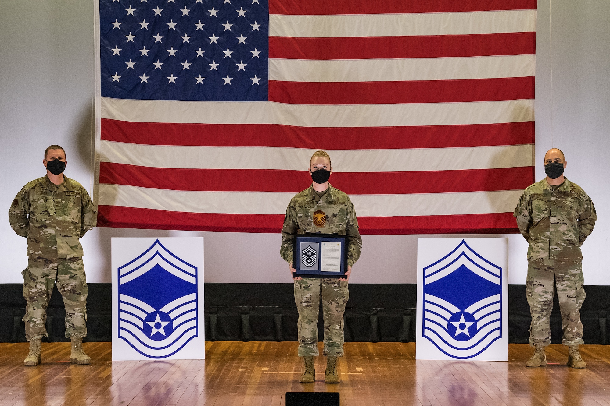 Master Sgt. Jessica Nienhueser, 436th Medical Support Squadron superintendent, stands between Col. Matthew Jones, 436th Airlift Wing commander, left, and Chief Master Sgt. Jeremiah Grisham, 436th AW interim command chief, as they pose for a photo during the senior master sergeant promotion release ceremony held at the base theater on Dover Air Force Base, Delaware, March 26, 2021. Nienhueser was one of 10 master sergeants at Dover AFB selected for promotion to senior master sergeant in the 21E8 promotion cycle. (U.S. Air Force photo by Roland Balik)