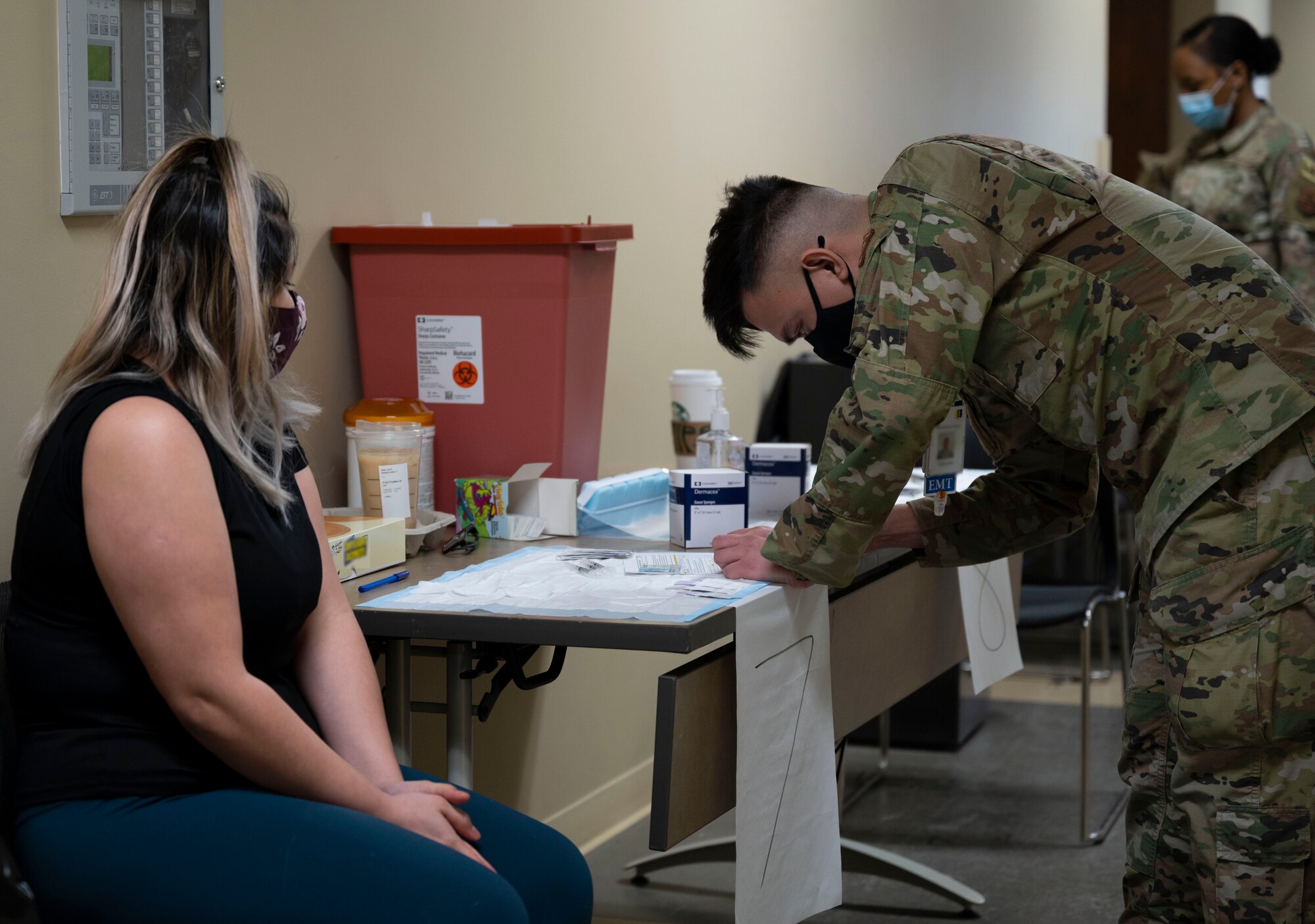 Maria Escobedo Galan, spouse of Staff Sgt. Matthew Escobedo, a 28th Operations Support Squadron noncommissioned officer in charge of aircrew flight equipment, prepares to receive her Pfizer COVID-19 vaccine from Senior Airman Cyrill Lueck, a 28th Medical Group immunization technician, during the 28th MDG point of distribution (POD) event at the Installation Deployment Readiness Center on Ellsworth Air Force Base, S.D., March 19, 2021. During the POD event, the 28th MDG provided approximately 1,250 beneficiaries with their first or second doses (if they received the first dose from the 28th MDG) of the Pfizer COVID-19 vaccine within a 12-hour period. (U.S. Air Force photo by Senior Airman Christina Bennett)